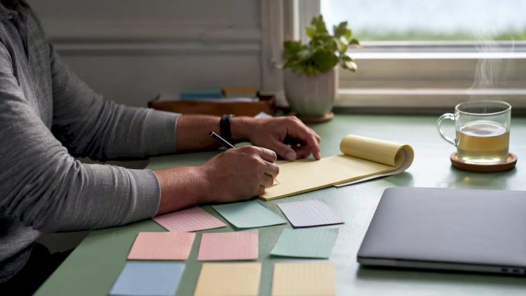 Hands arranging index cards on mint-green desk