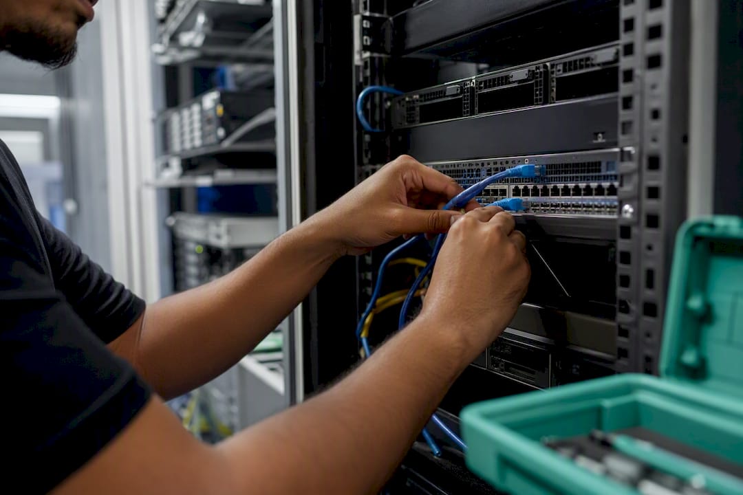 Hands connecting cable to server in data center