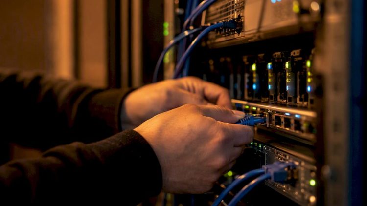 Hands connecting network cable in server rack