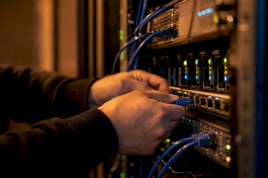 Hands connecting network cable in server rack